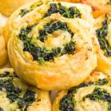 A spinach pinwheel sits on top several other pinwheels.